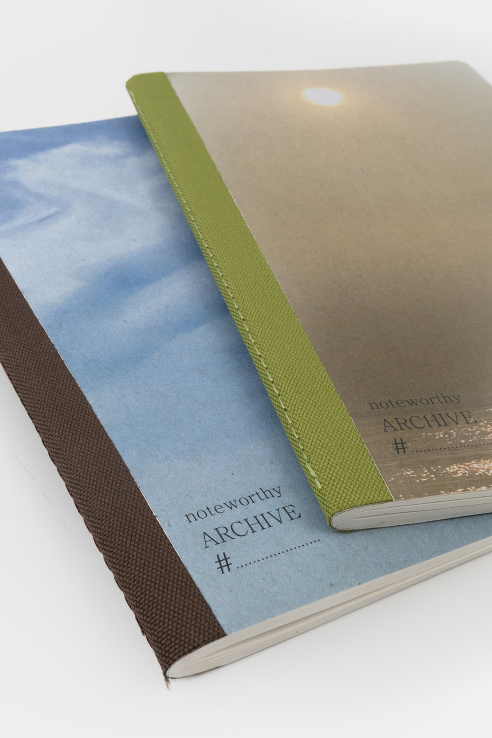 Two books a5 notebooks with covers featuring the sun and blue sky and stitched back