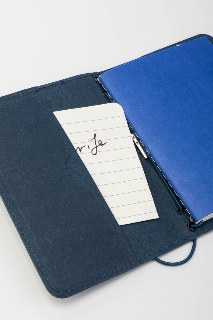 Opened blue passport size sketch journal with a note