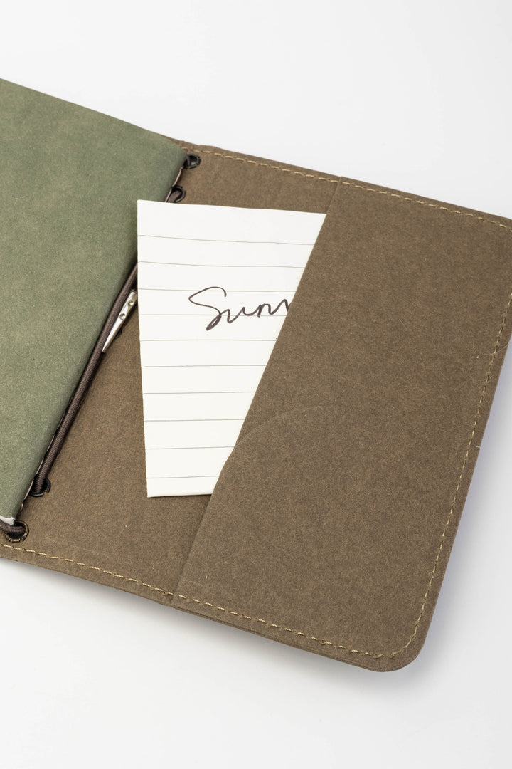 Opened green passport size sketch journal with a note