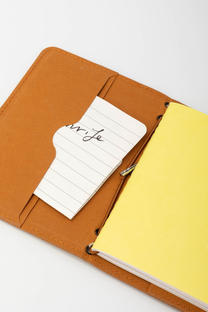 Open orange passport size sketch journal with a note