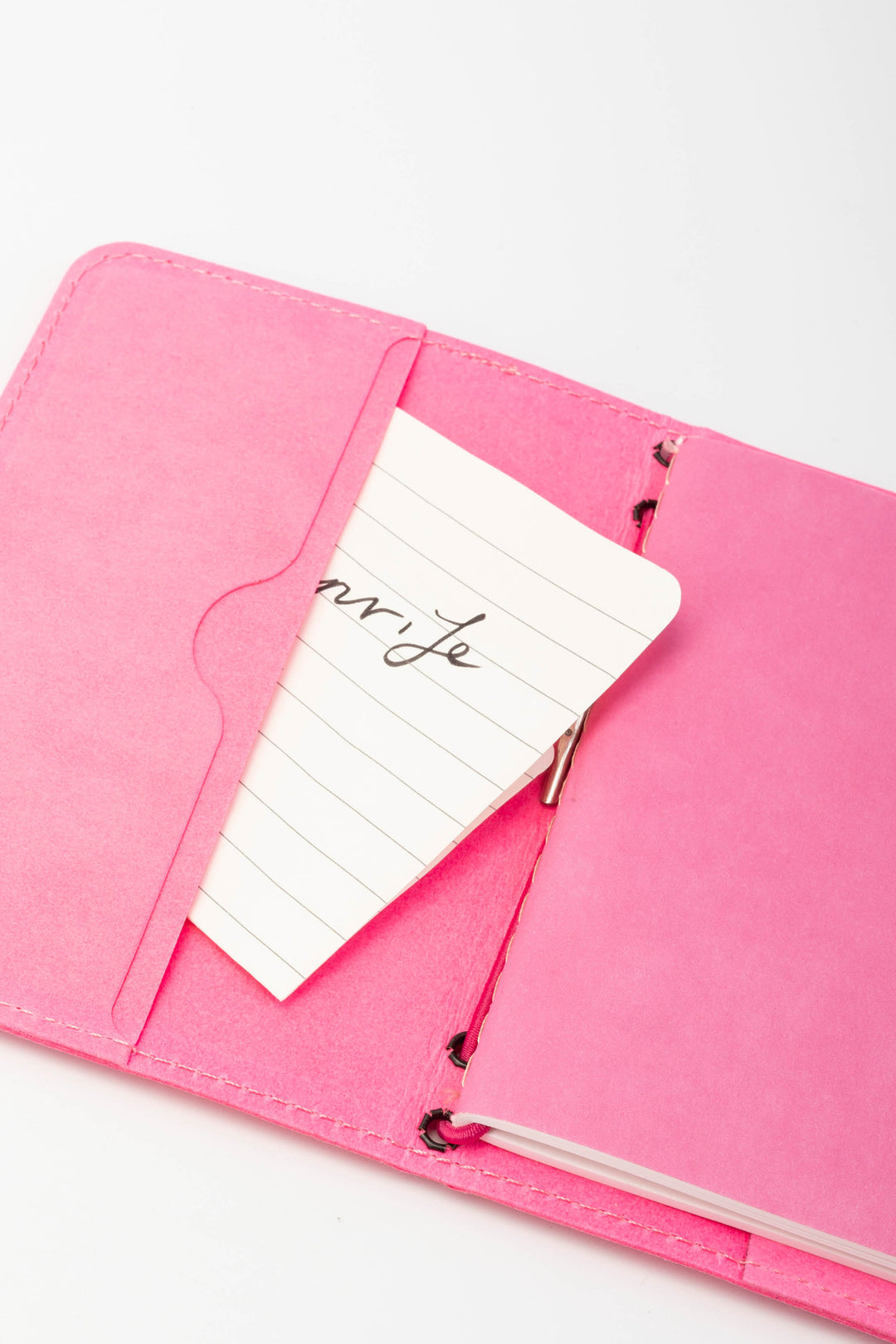 Open pink passport size sketch journal with a note
