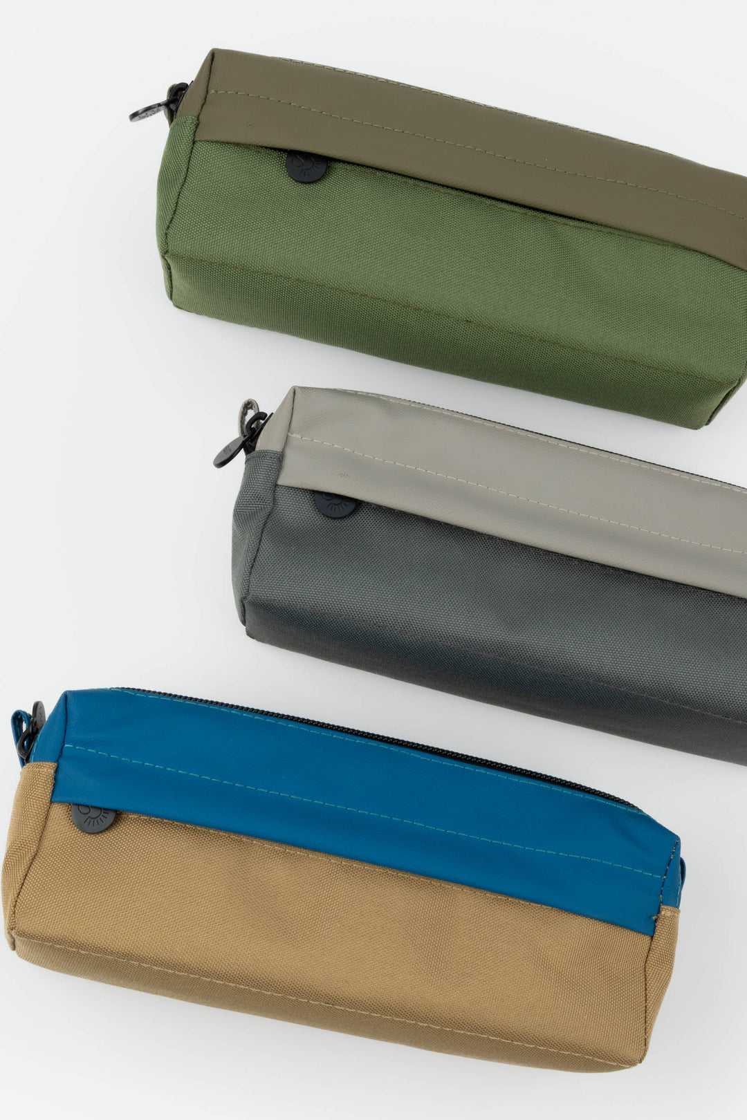 Three rectangular pencil cases in green, gray, and brown with blue accents on a white background.