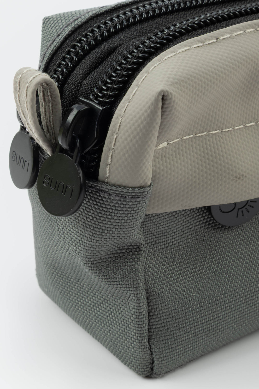 Close-up of a grey pencil case with a zipper and brand logo on a white background