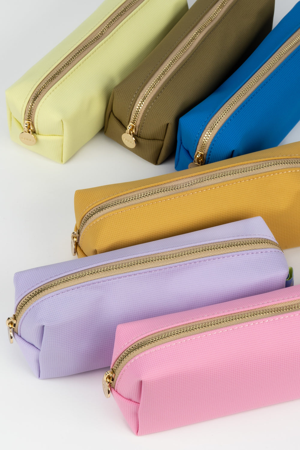 Colourful pencil cases with golden zippers on a light background