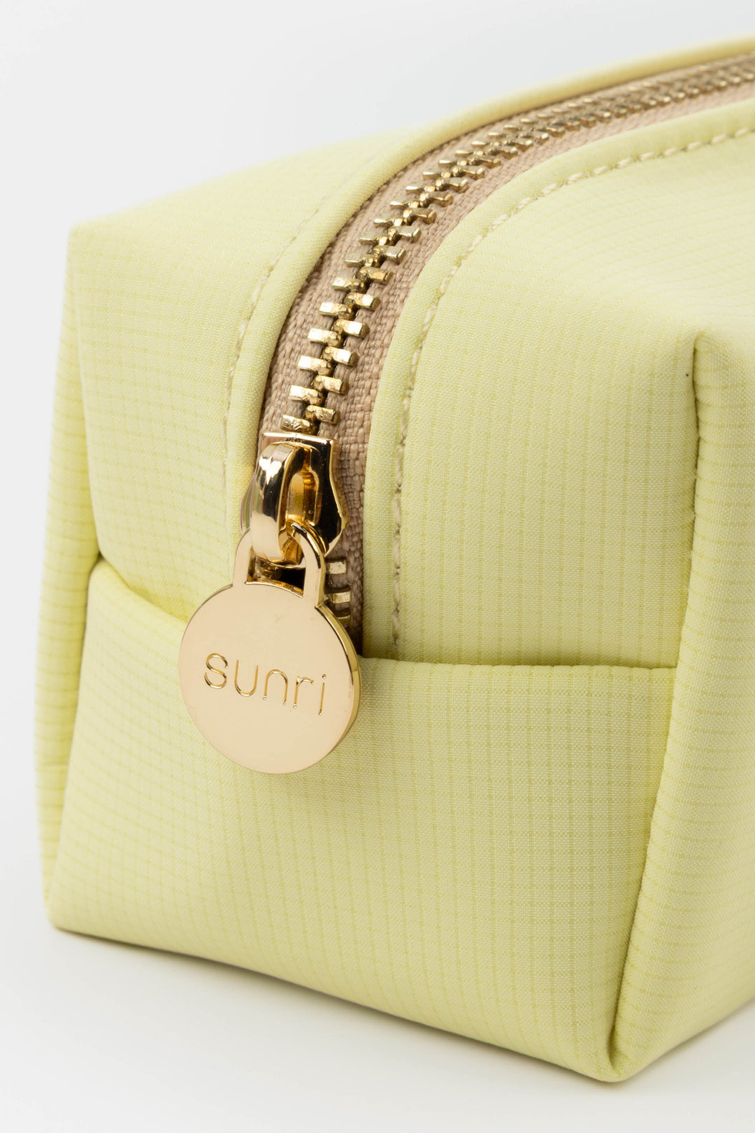 yellow pencil case with gold zipper and 'sunri' brand tag on a white background