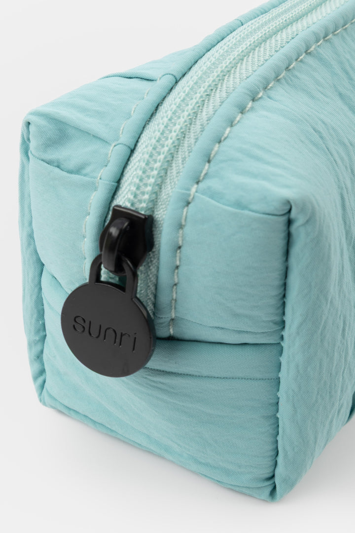 Teal zippered pouch with a black tag on a white background