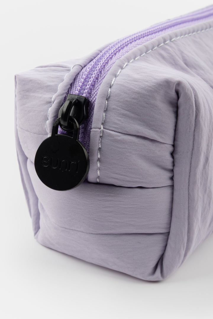 Purple pleated pouch with a black zipper and visible brand logo on a white background