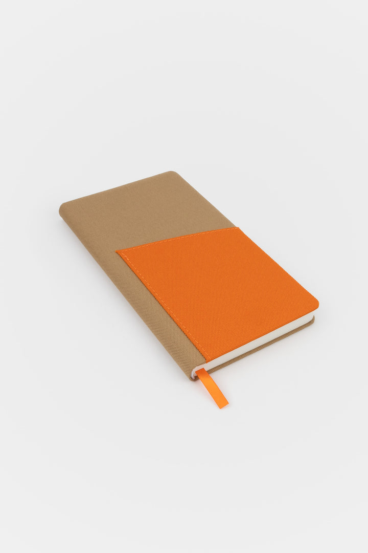 Closed brown pocket notebook with orange fabric front pocket and orange ribbon marker
