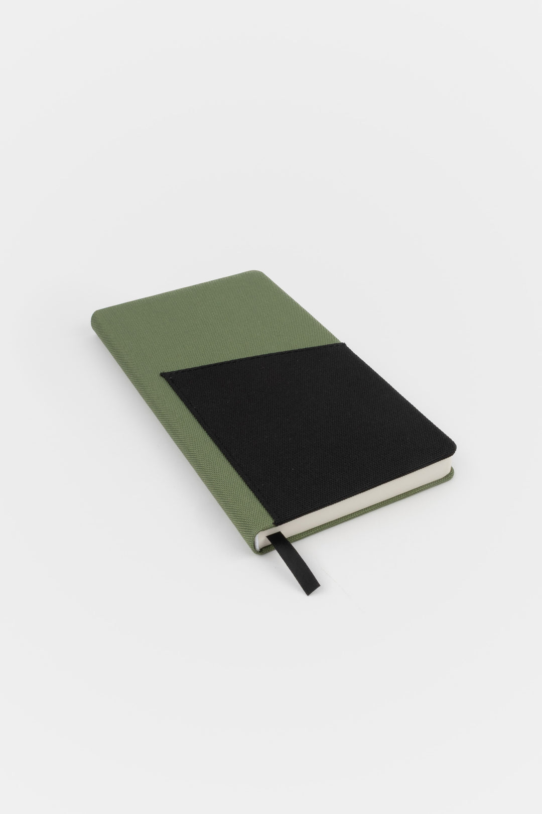 Closed green pocket notebook with black fabric front pocket
