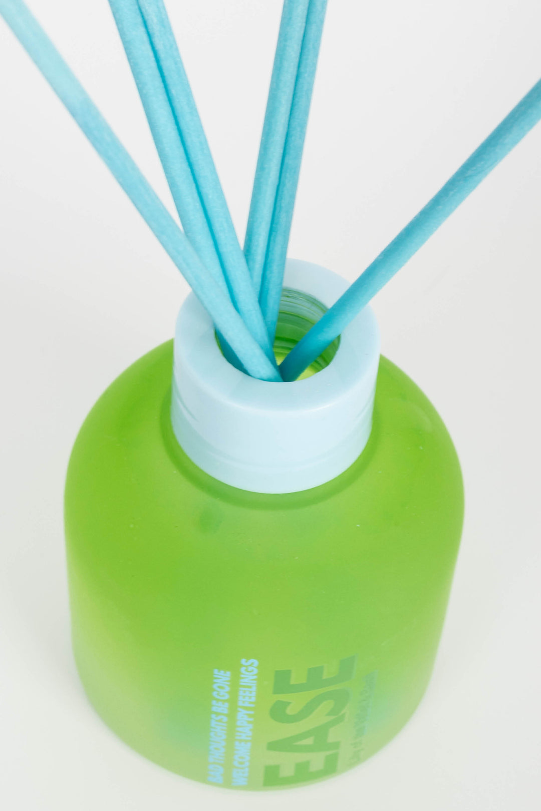 Green diffuser bottle with blue sticks on a white background