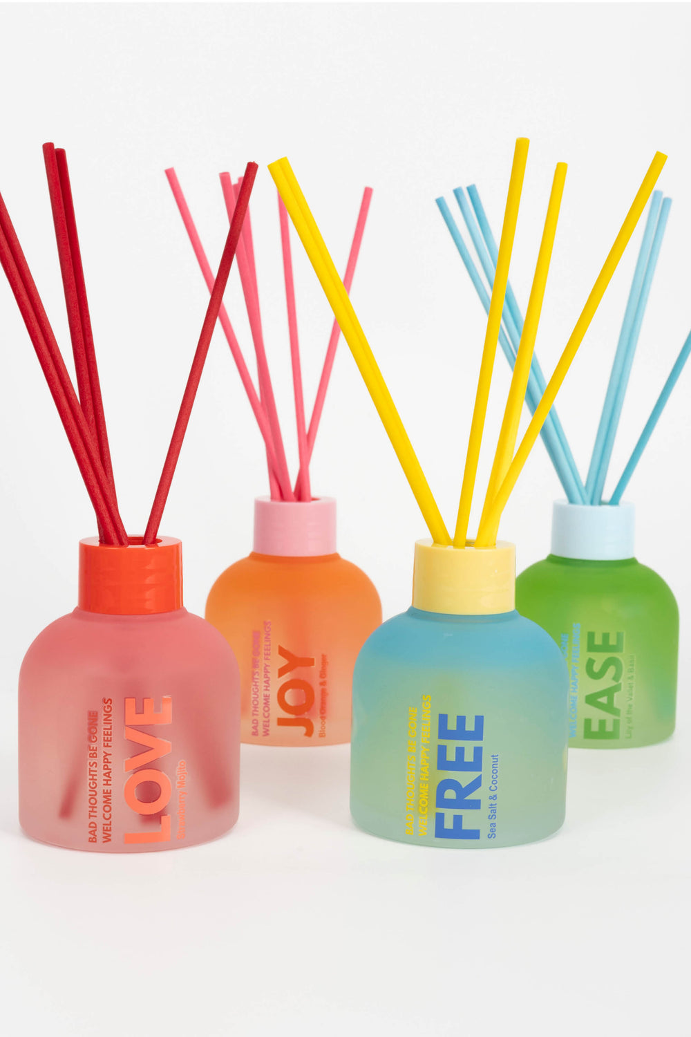 Set of four diffusers with colorful sticks and labeled caps on a white background