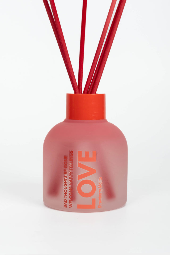 Pink diffuser bottle with red sticks on a white background