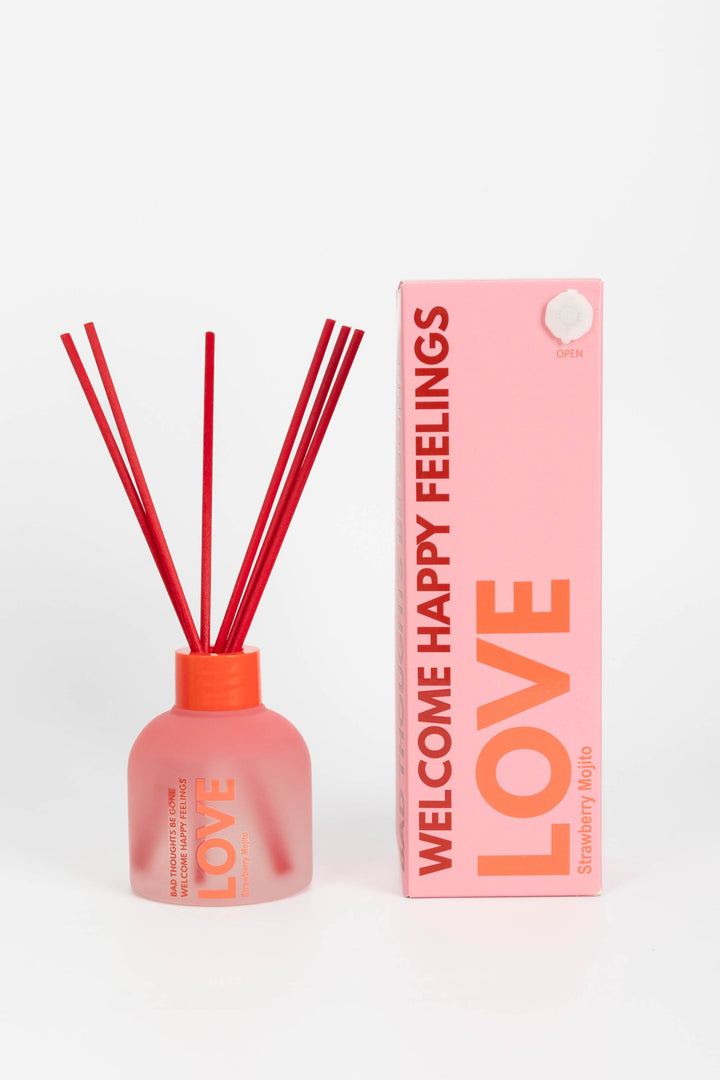 Pink diffuser bottle with red sticks and matching packaging on a white background