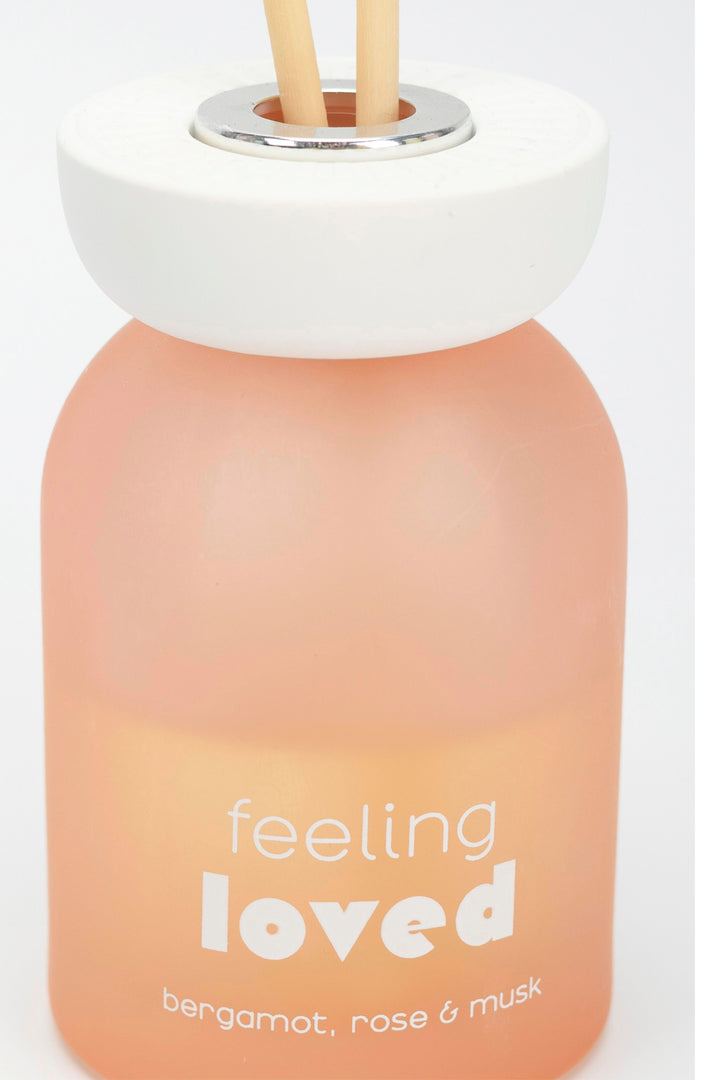 Diffuser bottle with 'feeling loved' text and gradient design on a white background