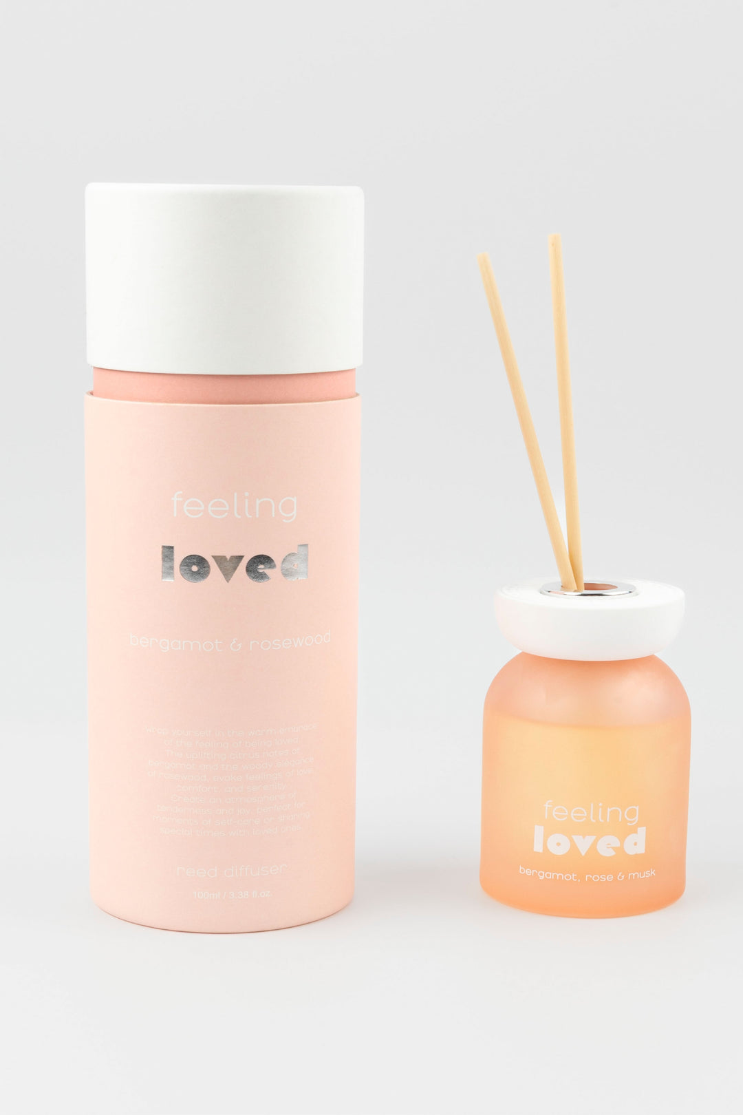 Pink diffuser bottle with white cap and 'feeling loved' text on a light gray background