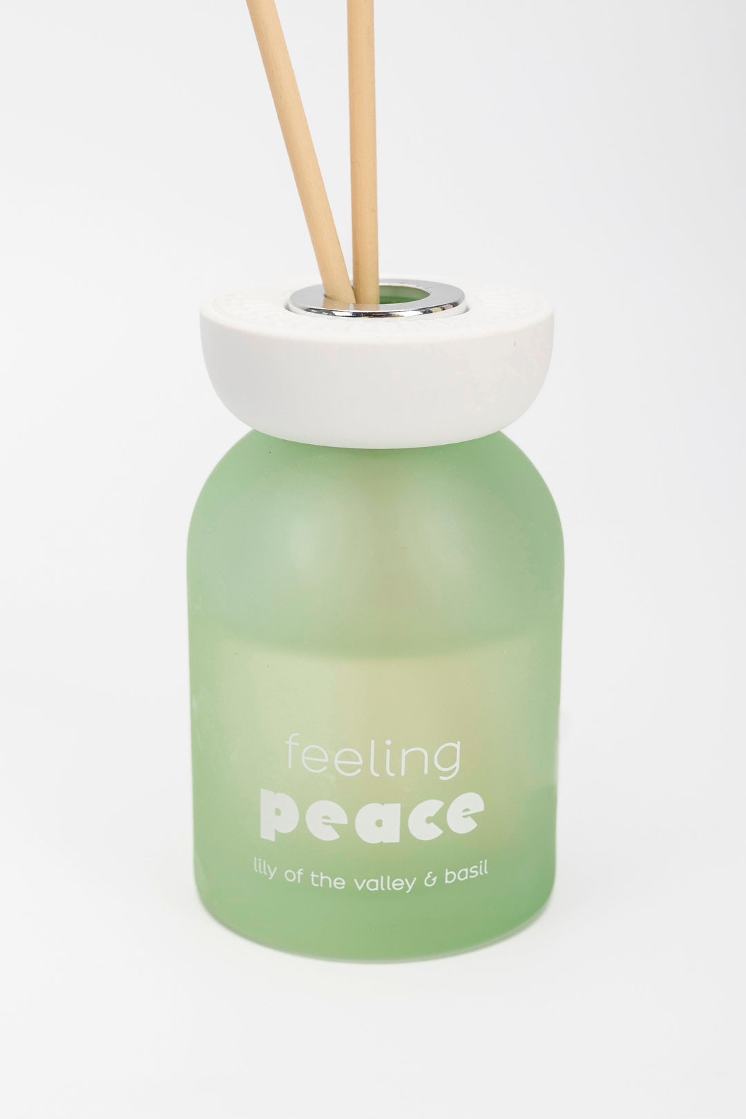 Green diffuser bottle labeled 'feeling peace' with wooden sticks on a white background