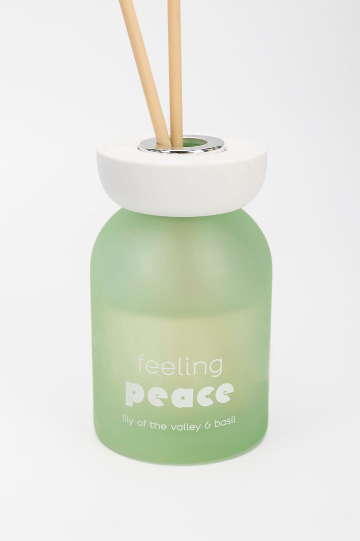 Green diffuser bottle labeled 'feeling peace' with wooden sticks on a white background