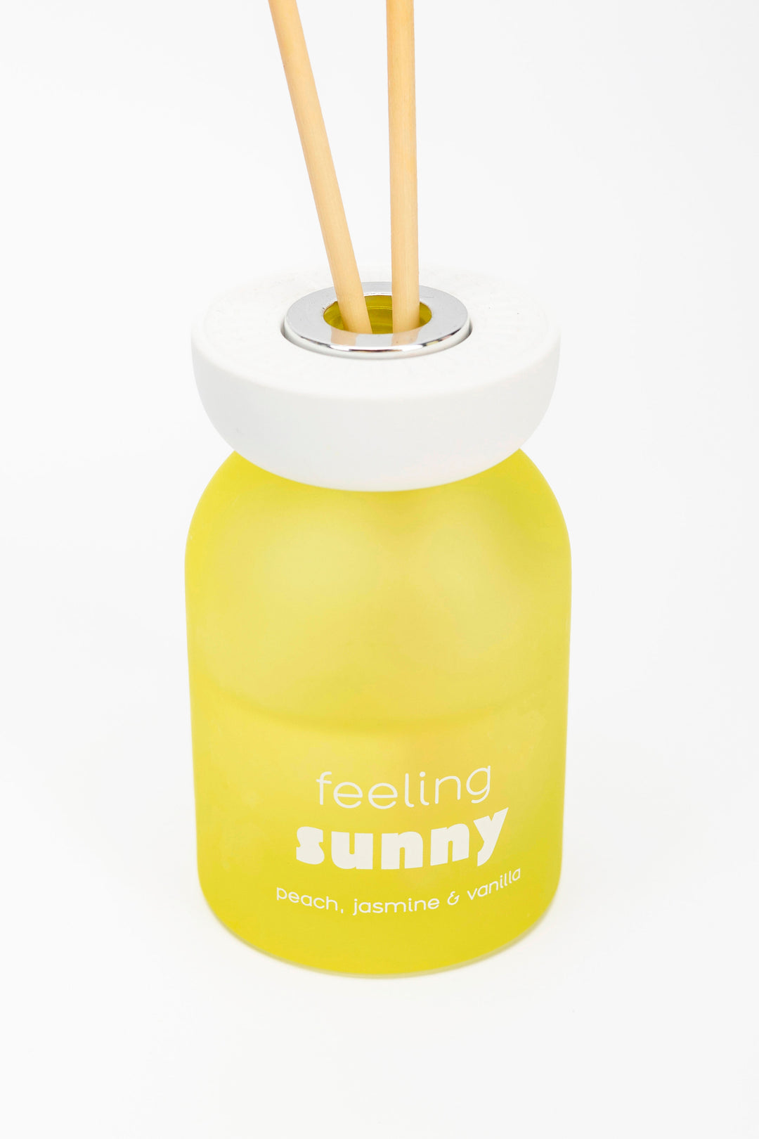 Yellow diffuser bottle labeled 'feeling sunny' with wooden sticks on a white background