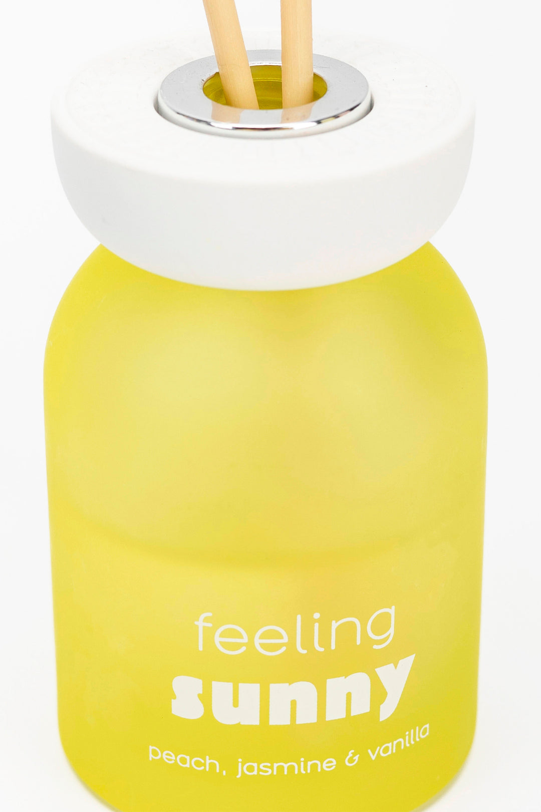 Yellow bottle with 'feeling sunny' text and wooden sticks on a white background