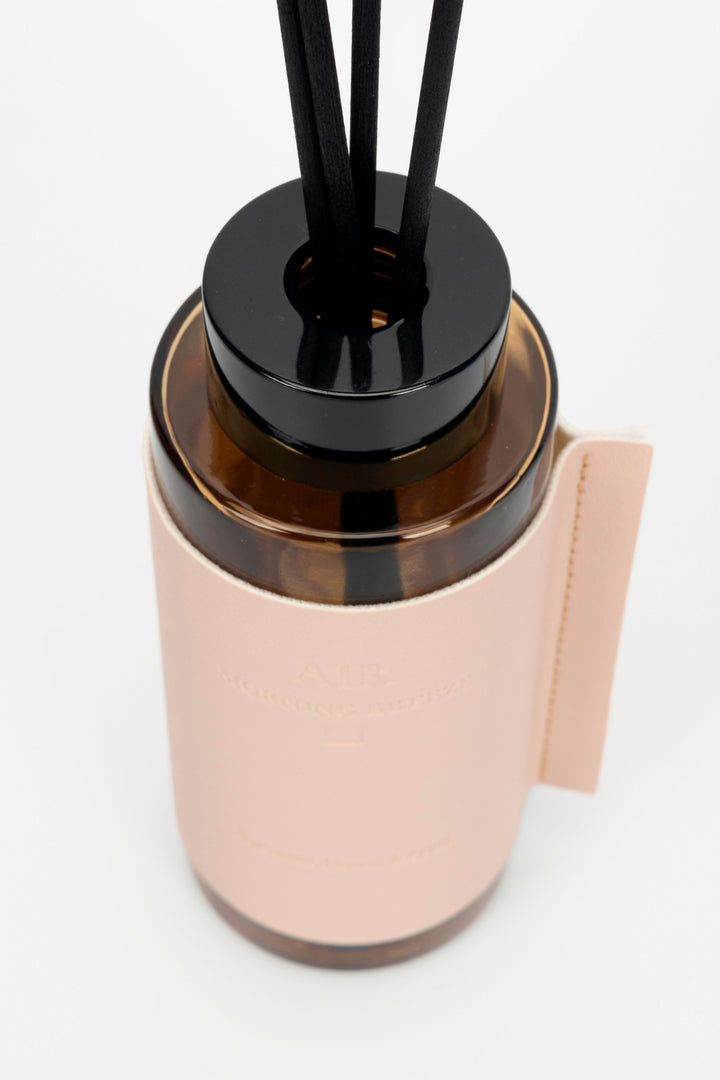 Beige covered diffuser bottle with black cap and reeds