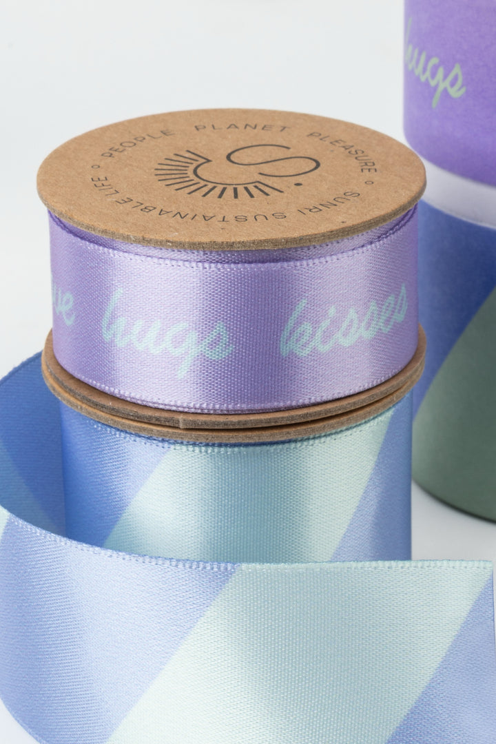 close up of lilac satin ribbon roll with hugs kisses wording

