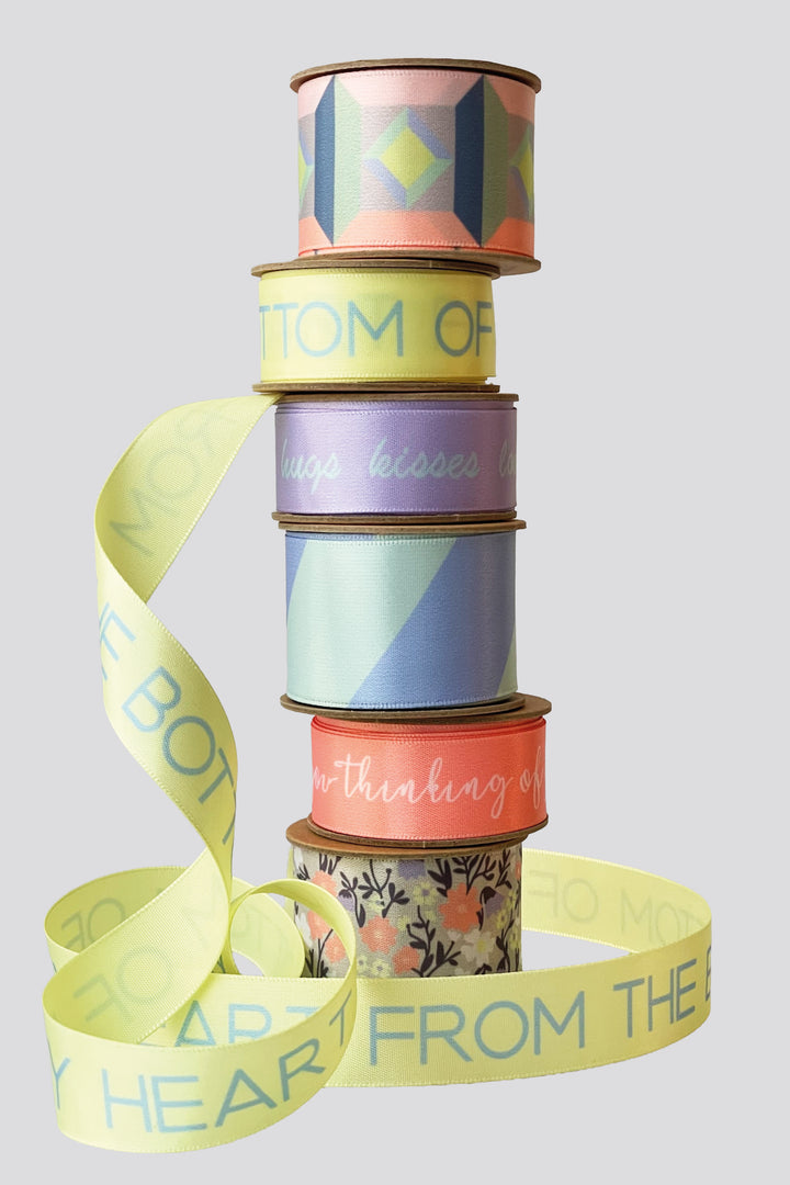 Stack of colorful ribbon spools with text on a light gray background