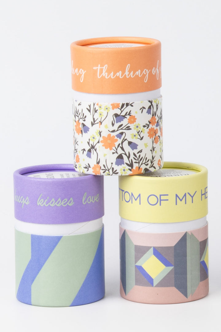 Set of three cylindrical containers with colorful lids and geometric patterns on a white background