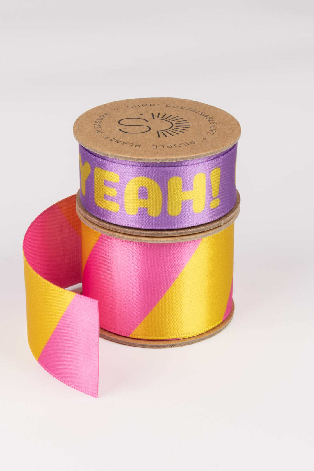 Spool of pink and yellow striped ribbon with 'YEAH!' text on a white background
