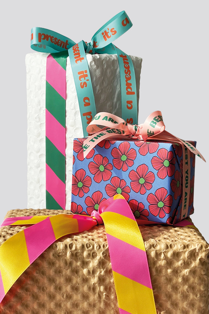 Stack of wrapped gifts with colorful ribbons on a textured surface