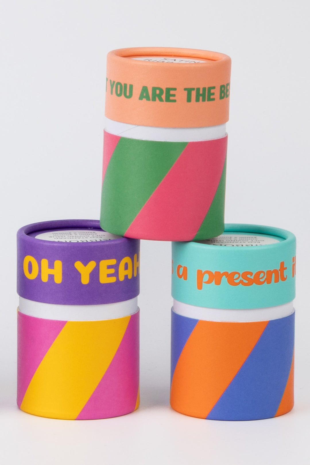 three printed paper cans containing satin ribbon packs shown in mixed colours and patterns on white surface