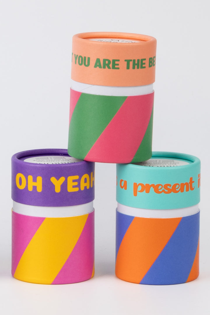 three printed paper cans containing satin ribbon packs shown in mixed colours and patterns on white surface