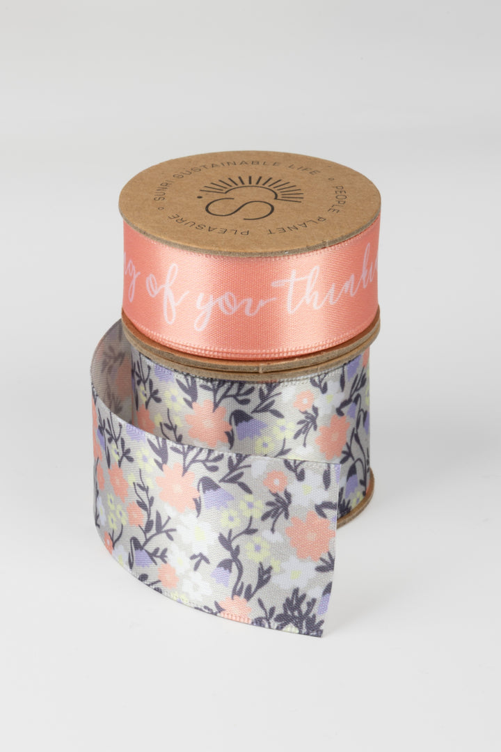 Jar with floral ribbon and pink label on a white background