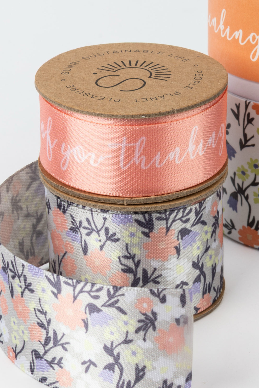Spools of ribbon with floral patterns and text on a white background