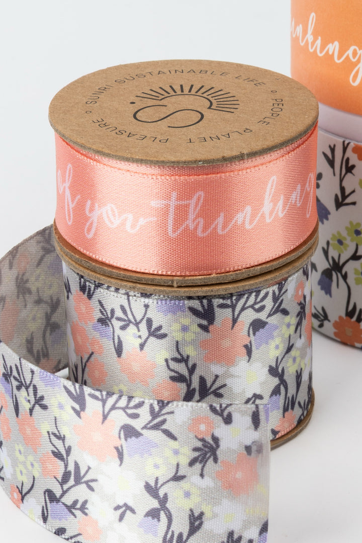 Spools of ribbon with floral patterns and text on a white background
