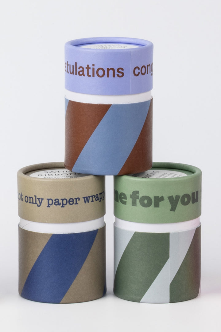 Three rolls of colorful paper wrap stacked on a white background