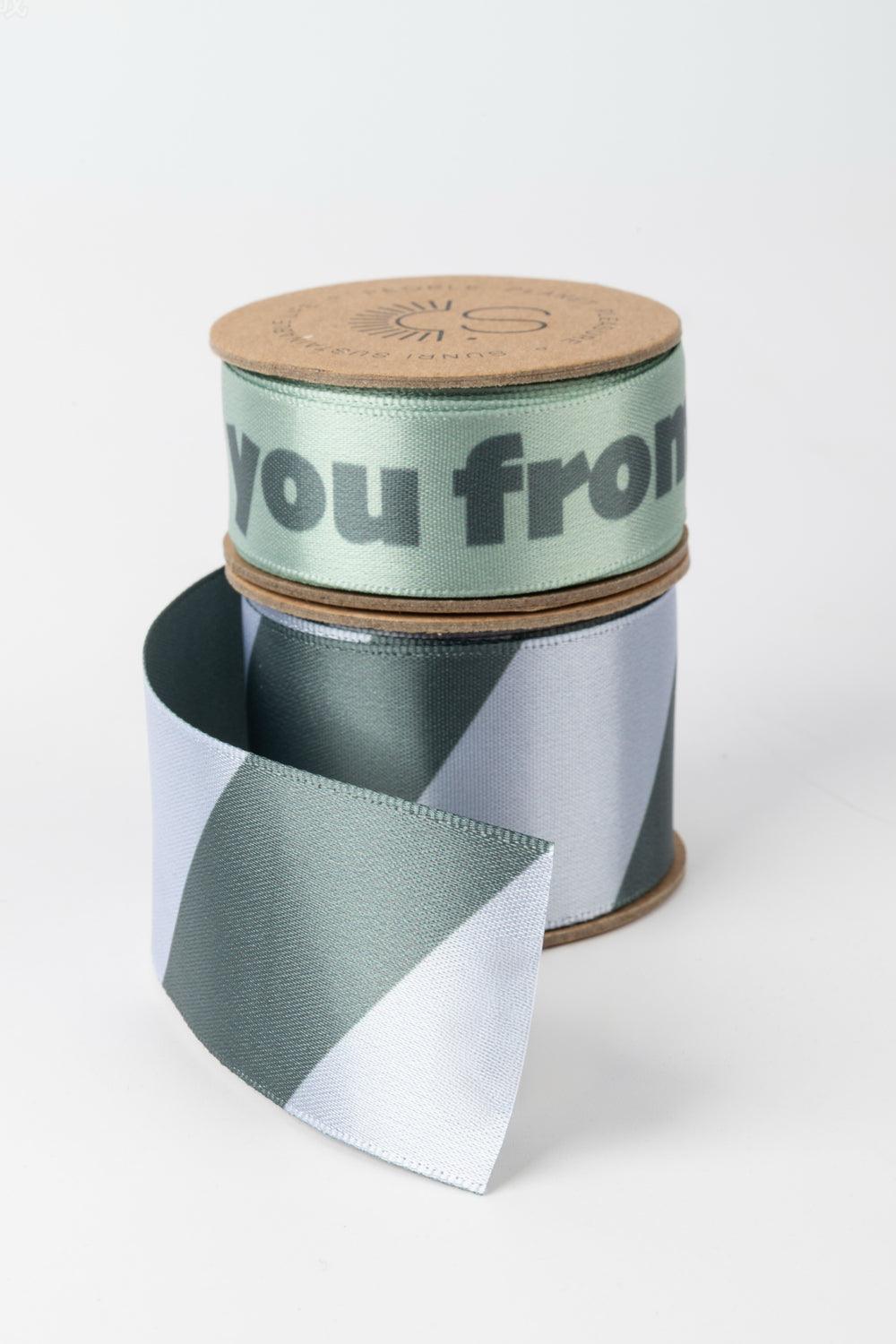 Spool of ribbon with a cardboard tube labeled 'you from' on a white background