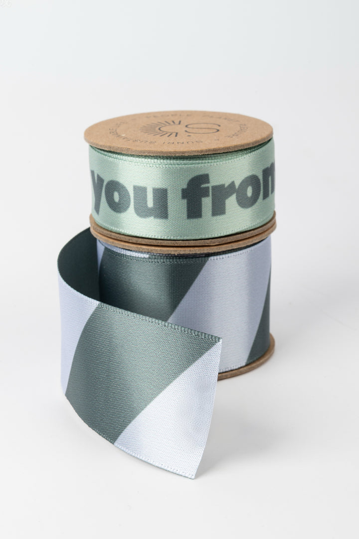 Spool of ribbon with a cardboard tube labeled 'you from' on a white background