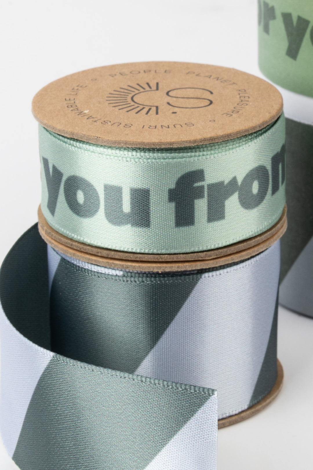 Green ribbon with 'you from' text on a spool, branded with a logo.