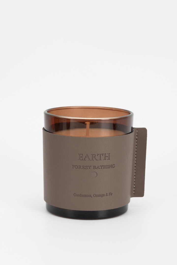 Candle in a brown holder with 'Earth' branding on a white background