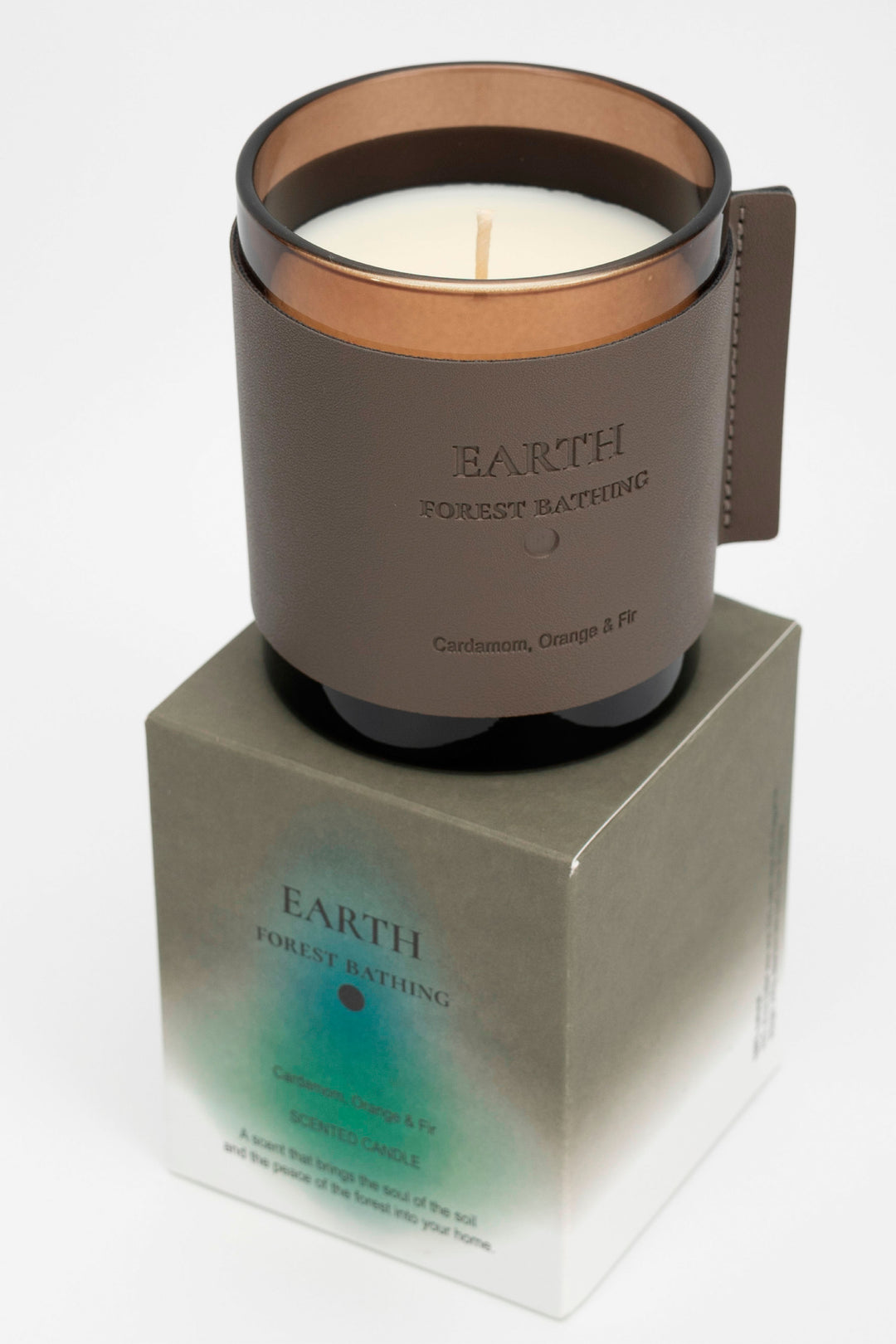 Candle in a brown holder with 'Earth' branding on a white background