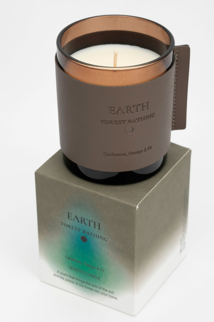 Candle in a brown holder with 'Earth' branding on a white background
