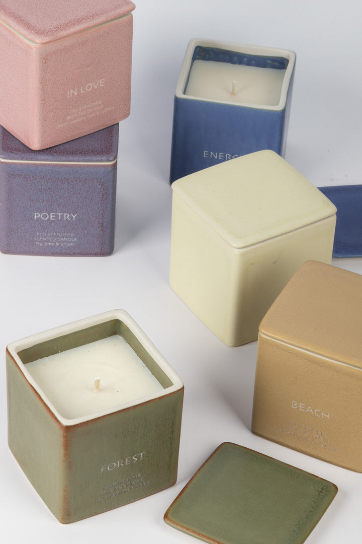 assorted square ceramic candles in mixed colours with open and closed lids
