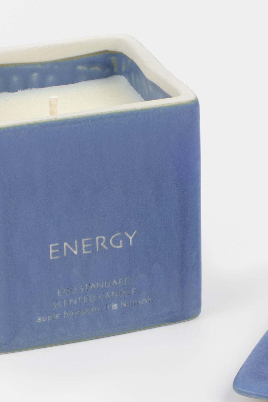 open blue ceramic candle showing white wax and wick, close-up front view

