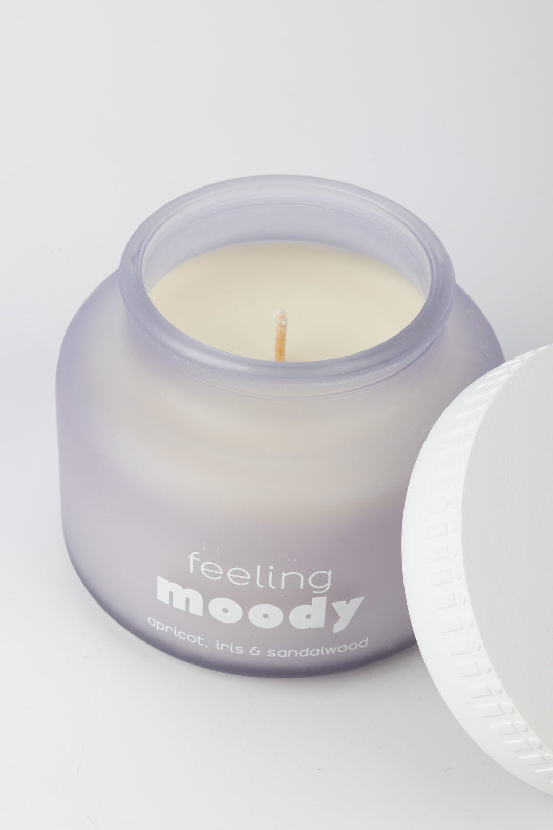 Candle in a purple jar labeled 'feeling moody' on a white background
