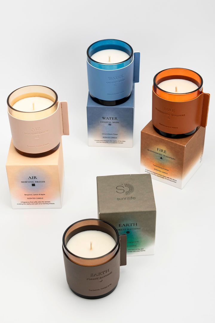 Four candles in different colors with their respective boxes on a white background