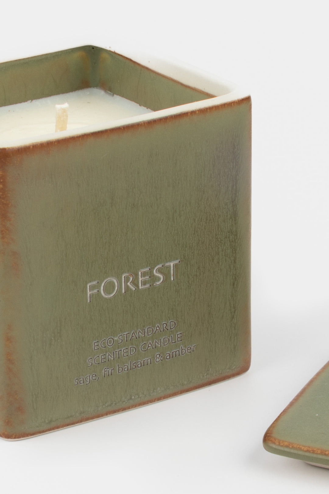 open green ceramic candle showing white wax and wick, close-up front view

