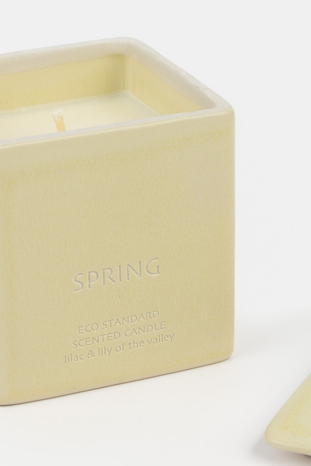open cream ceramic candle showing white wax and wick, close-up front view
