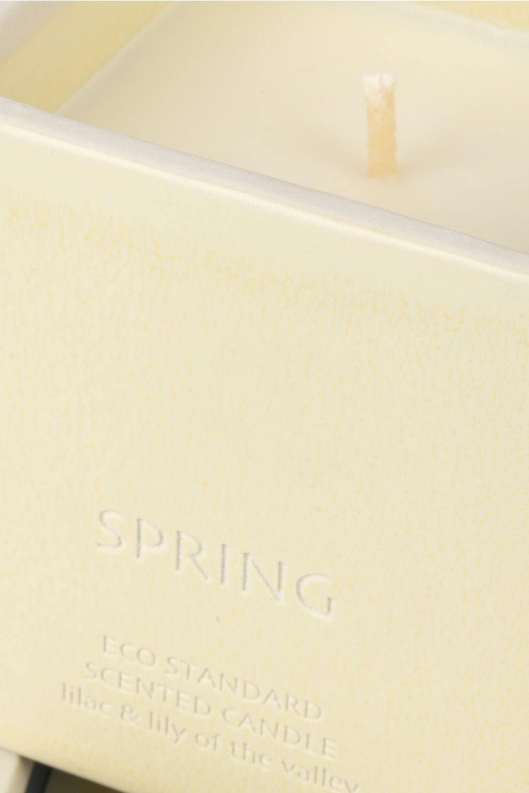 close-up of cream ceramic candle rim with visible wick and wax
