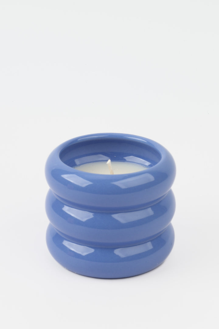 blue glossy ceramic candle holder with rounded stacked shape and white wax inside

