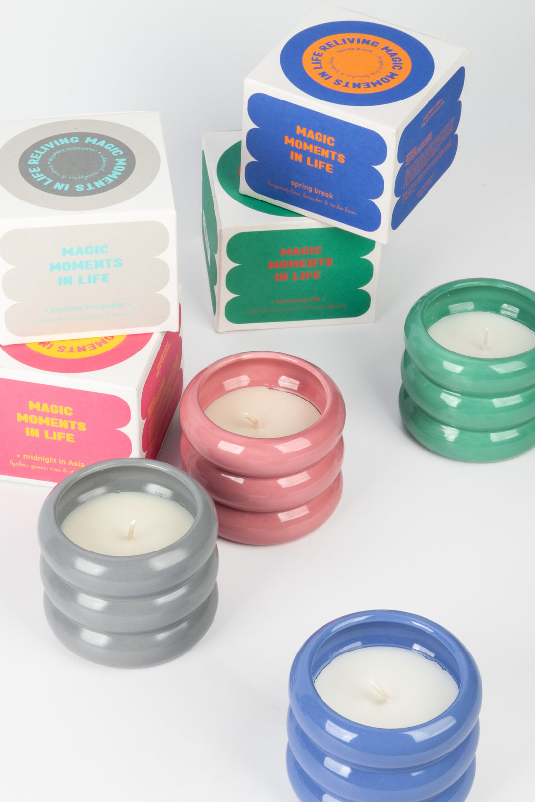 assorted colourful round ceramic candles displayed with printed packaging boxes
